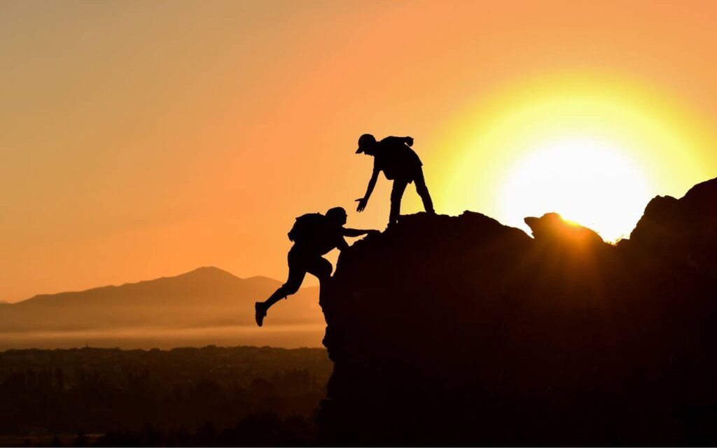 手を伸ばす人と登山してる人